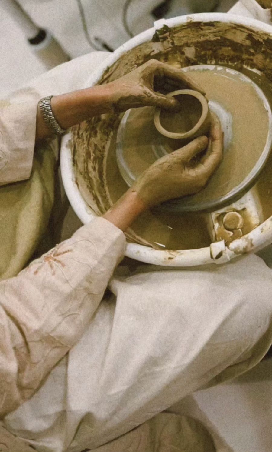 Woman in an abaya hand building a clay bowl at ROA Art studio
